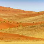 Crestas de dunas anaranjadas con una cara iluminada y otra en sombra al amanecer