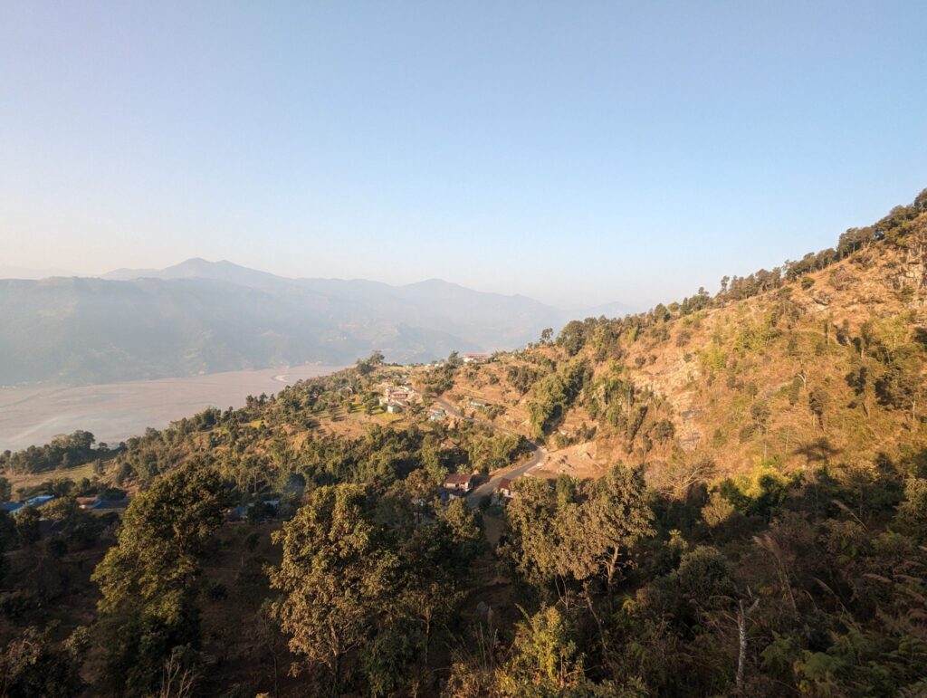 Pista de tierra excavada en la ladera sobre un río de aguas grises