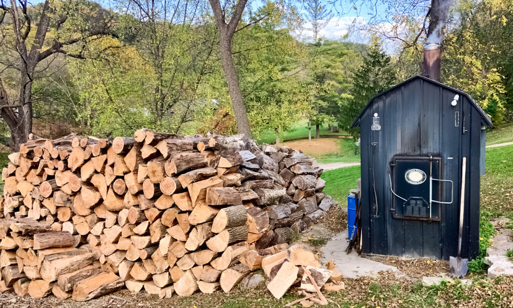 Interior de sauna de madera con banco, estufa de leña y cubo con cazo