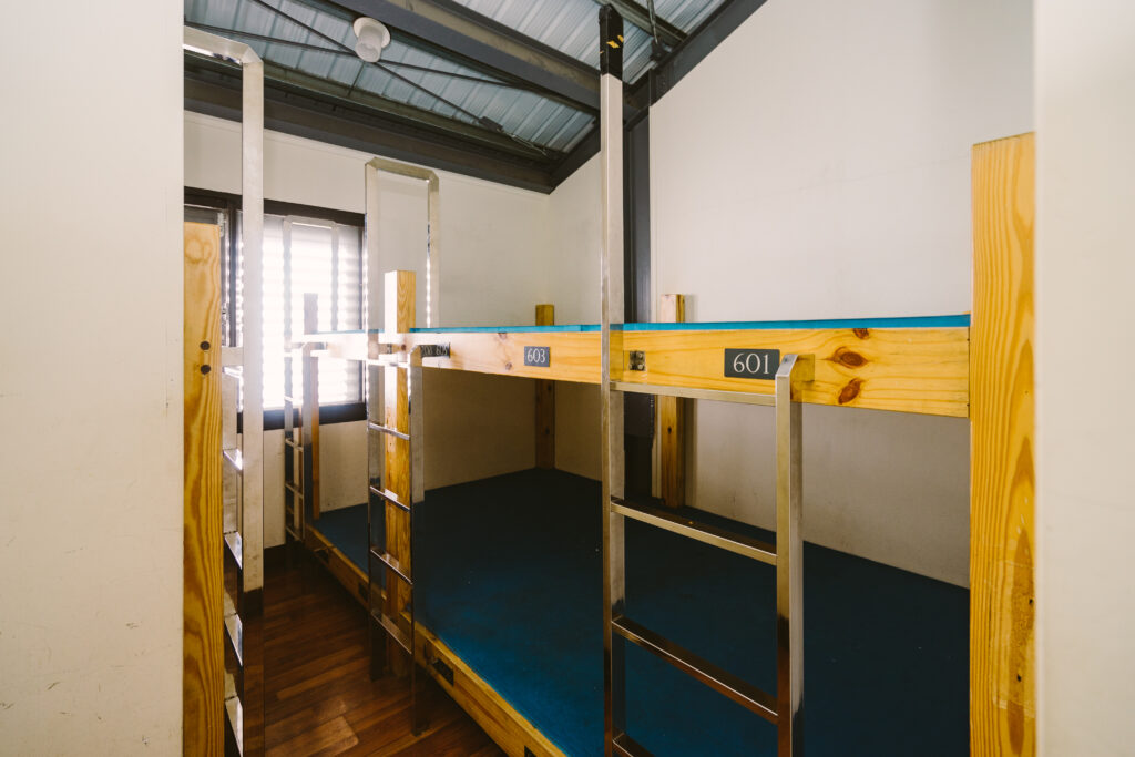 Literas de madera con mantas dobladas en una sala pequeña sin calefacción