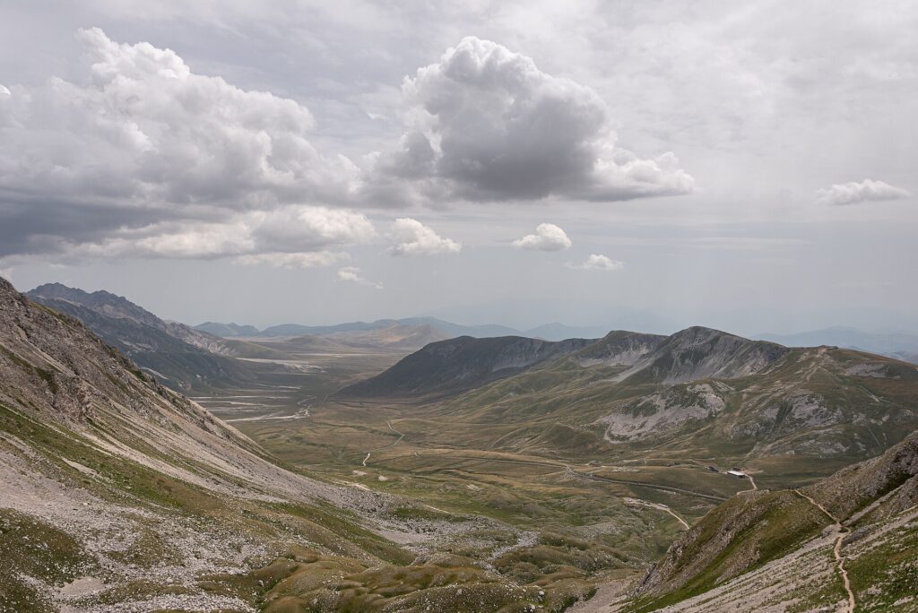 Camino de tierra cruzando una meseta amplia con cumbres nevadas al fondo