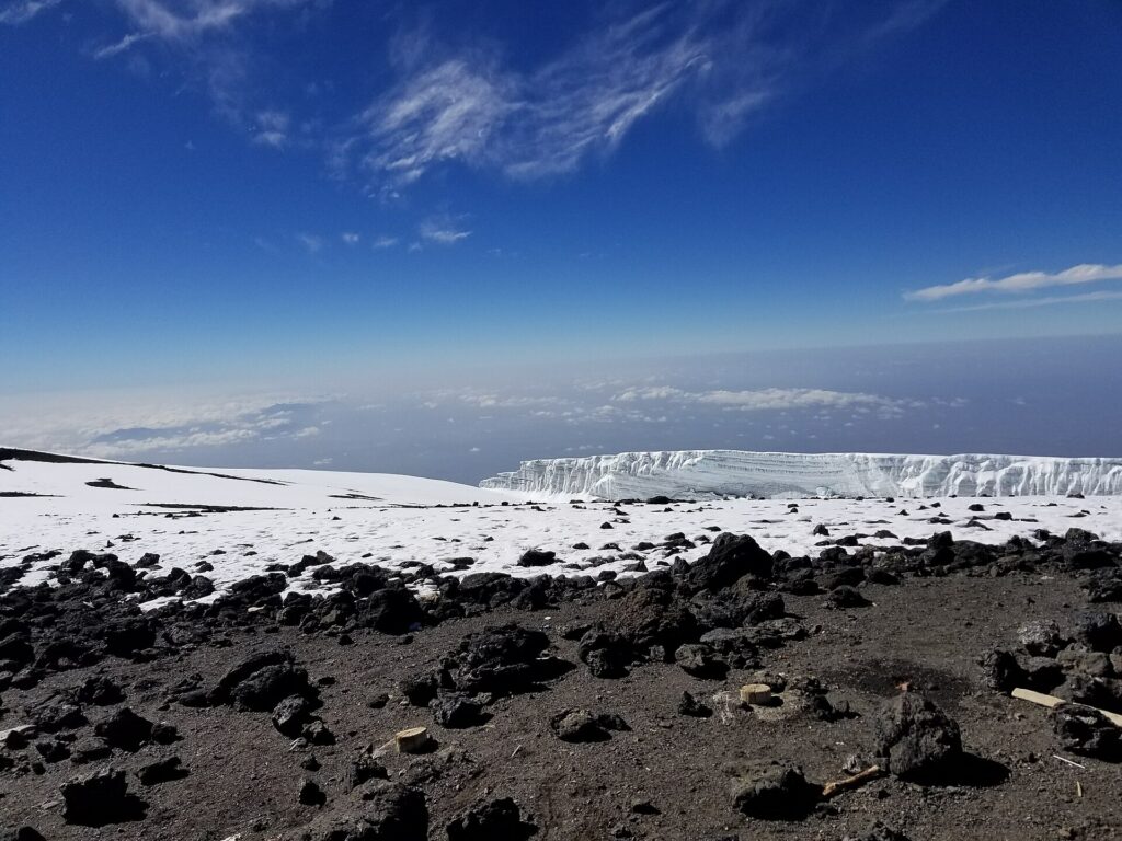 Campamento de tiendas amarillas sobre terreno pedregoso con nubes por debajo del nivel del suelo