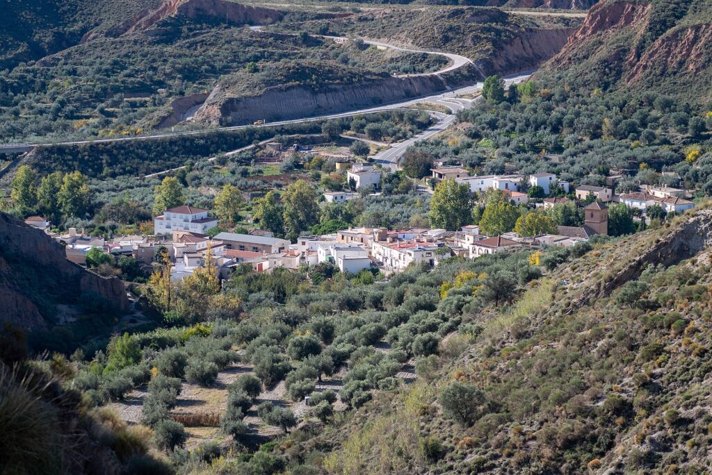 Pueblo blanco escalonado en una ladera con cumbres nevadas asomando por detrás