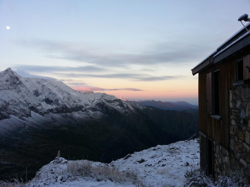 Refugio de montaña de piedra sobre terreno volcánico con la primera luz del amanecer