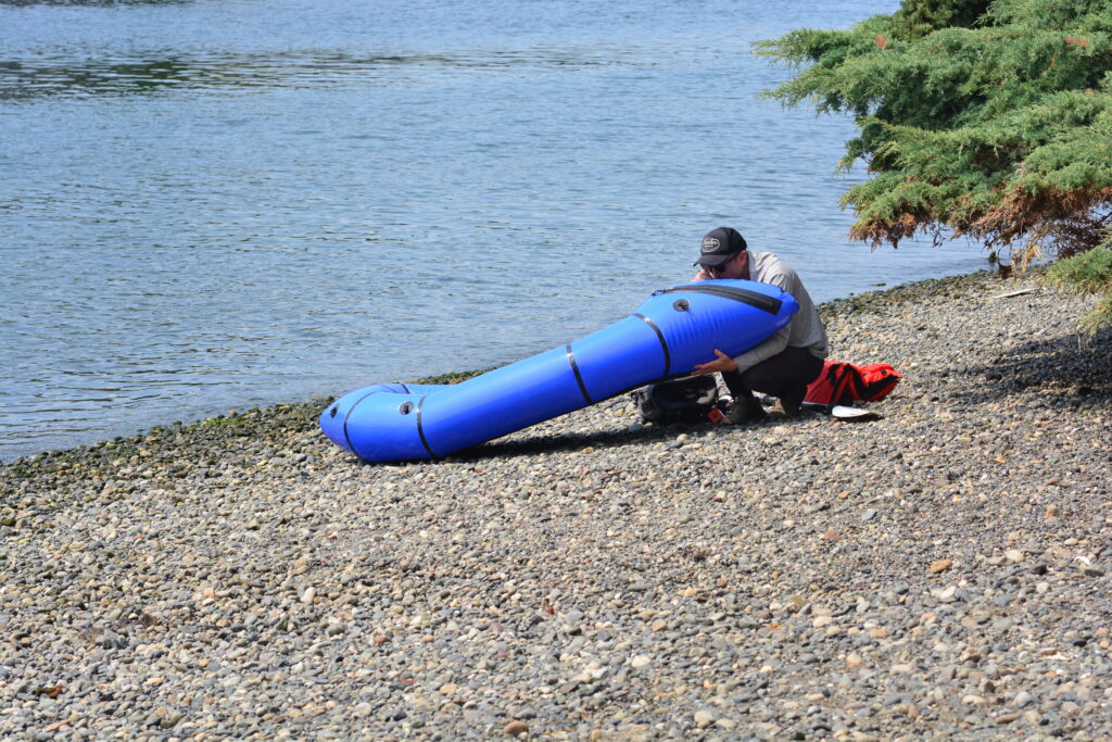 Kayak hinchable siendo inflado con una bomba de pie sobre la arena de una playa