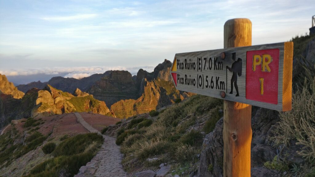 Cresta rocosa entre nubes bajas con un sendero estrecho serpenteando hacia la cima