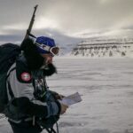 Brújula sobre un mapa topográfico sujeto con las manos en un entorno de montaña con niebla
