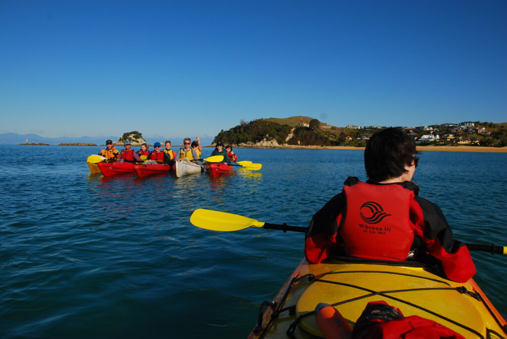 Kayak de mar rígido avanzando sobre olas moderadas con el remero inclinado hacia adelante