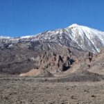 Cima volcánica rojiza del Teide con nieve residual y vistas al mar de nubes al amanecer