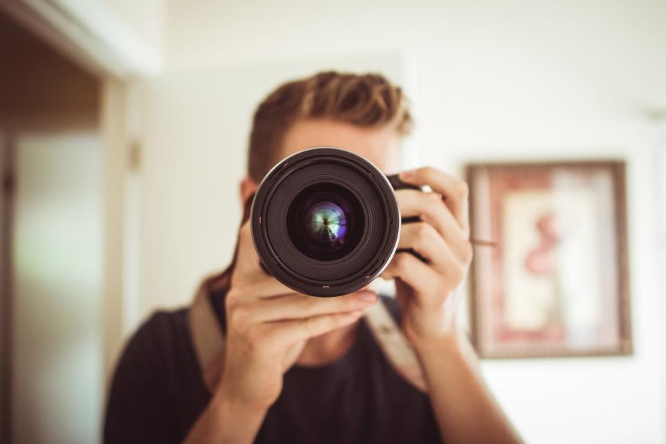 Objetivo fotográfico junto a un cepillo y una pera de aire sobre una superficie neutra